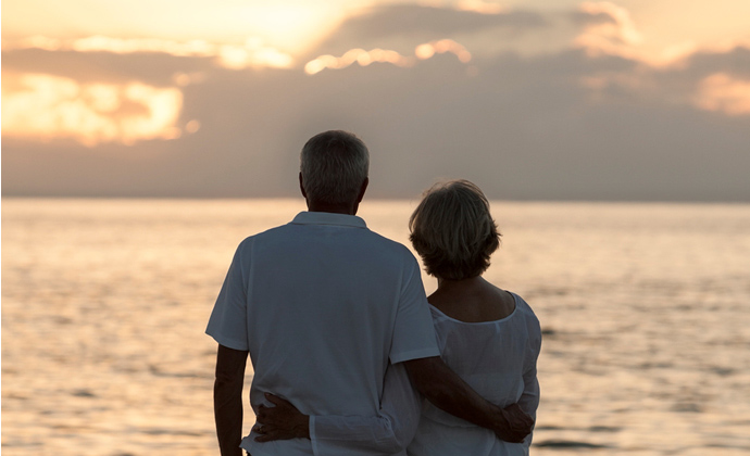 A couple looks out at a sunset over the ocean