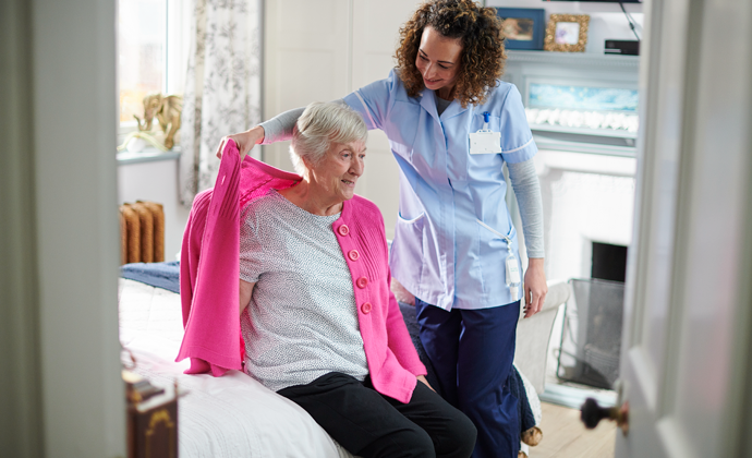 A nurse helps a patient dress.
