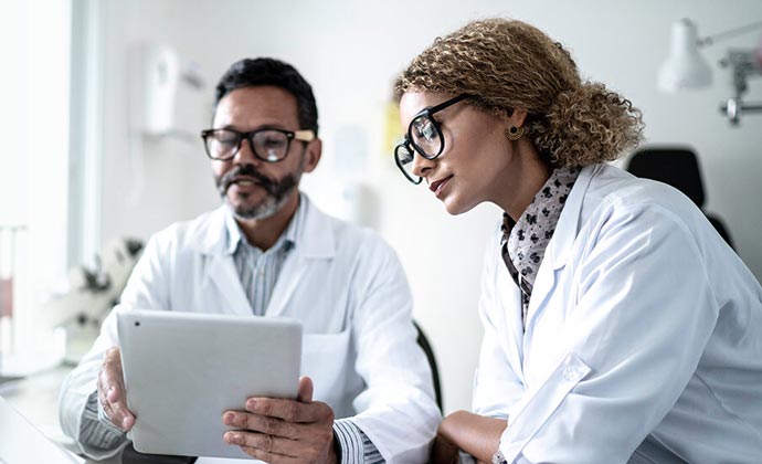 Two doctors read information from the same tablet.