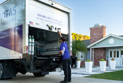 A delivery truck driver opens the back of his truck in front of a home